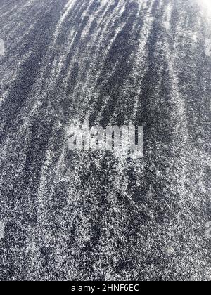 Background of asphalt with snow on a sunny, winter day. Slippery road Stock Photo
