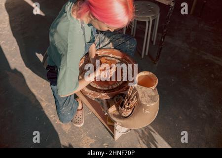 Young female artisan concentrated on modeling clay in workroom Stock Photo