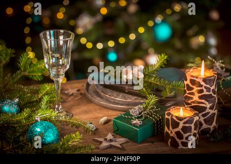 Christmas table setting with empty black ceramic plate, fir tree branches and green gift boxes on dark wooden background Stock Photo
