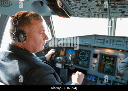 Male pilot sitting in cockpit of passenger airplane Stock Photo