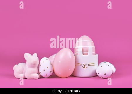 Pink and white painted easter eggs and cute easter egg cup in shape of bunny on pink background Stock Photo