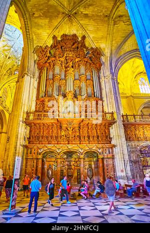 SEVILLE, SPAIN - SEPT 29, 2019: The carved wooden organ of Seville Cathedral with stone arches and columns, on Sept 29 in Seville Stock Photo