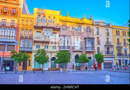 The beautiful historic townhouses, decorated with moulding, wall sculptures and cast-iron balconies in San Francisco Square, Seville, Spain Stock Photo