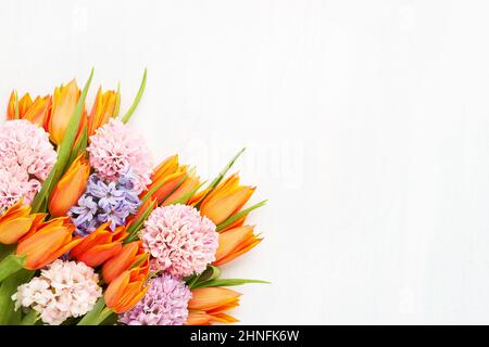 Bright orange tulips and pink hyacinth flowers bunch on a light background. Flat lay, copy space for text Stock Photo