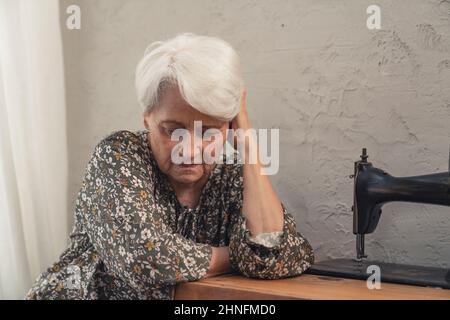 grey-haired caucasian grandmother sitting alone during grandparent's day and touching her head. High quality photo Stock Photo