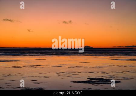 Sunset glows across Cook Inlet and behind Mount Redoubt from Anchorage, Alaska. Stock Photo