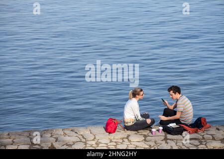 Picture of two persons,a couple,  white caucasian male and female, sitting in the streets of Belgrade, serbia, holding cups of coffee and drinking tak Stock Photo