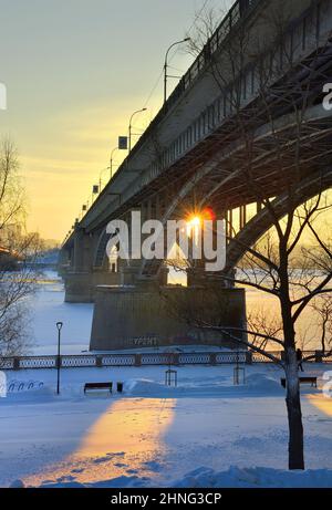 Novosibirsk, Siberia, Russia, 29.01.2022. Bridges on the winter embankment. The sun through the pillars of the Communal arch bridge over the Ob River Stock Photo