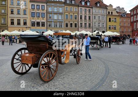 Warsaw, Poland-05.05.2018: Old horse-drawn carriages await tourists at the old town Market square in the centre of Warsaw. The driver is talking on th Stock Photo