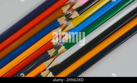 Many colored pencils are arranged around the edges of the image as a frame. In the center is an empty background with space for text. Mock up with copy space. Stock Photo