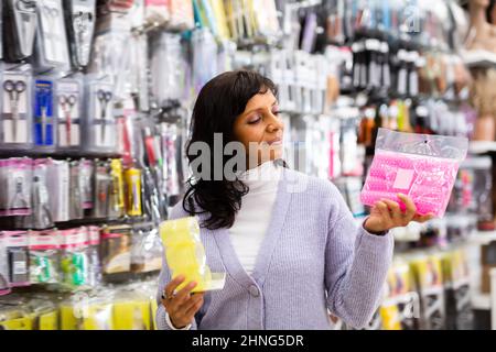 Smiling latina choosing hair rollers in store Stock Photo