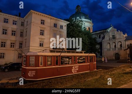 Old red city tram converted into street cafe against Dominican Cathedral Church. Stock Photo