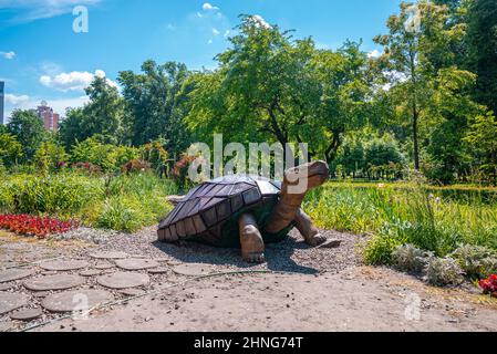 Wooden turtle sculpture beside pavement in garden on sunny day Stock Photo