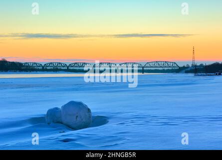 Morning on the banks of the Ob. A snow-covered bank of a large river at dawn, a railway bridge on the horizon. Novosibirsk, Siberia, Russia, 2022 Stock Photo