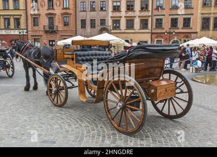 Warsaw, Poland-05.05.2018: Old horse-drawn carriages await tourists at the old town Market square in the centre of Warsaw. The driver is talking on th Stock Photo