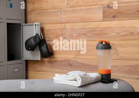 Bottle of water and towel on bench in locker-room Stock Photo