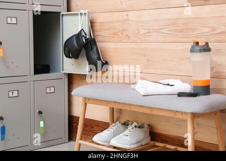 Locker with sport equipment and bench in change-room Stock Photo