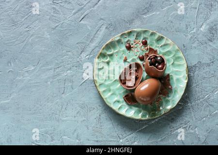 Plate with broken chocolate Easter eggs on color background Stock Photo