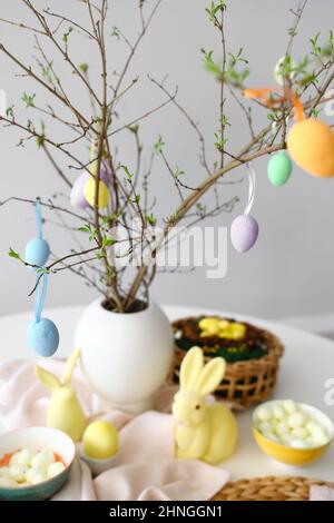 Tree branches decorated with Easter eggs on served table Stock Photo