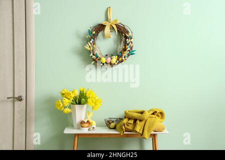 Table with beautiful tulips, knitted sweaters and stylish Easter decor near color wall Stock Photo