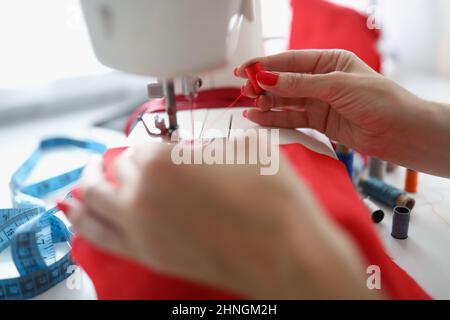 Female hands thread red thread into a sewing machine Stock Photo