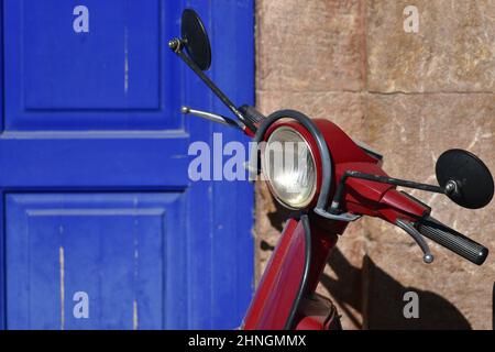Original red vintage Vespa against a stone wall with blue wooden doors in Nafplio, Peloponnese Greece. Stock Photo