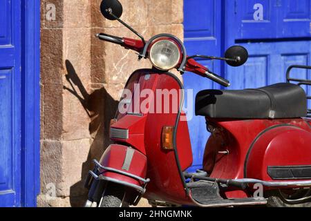 Original red vintage Vespa against a stone wall with blue wooden doors in Nafplio, Peloponnese Greece. Stock Photo