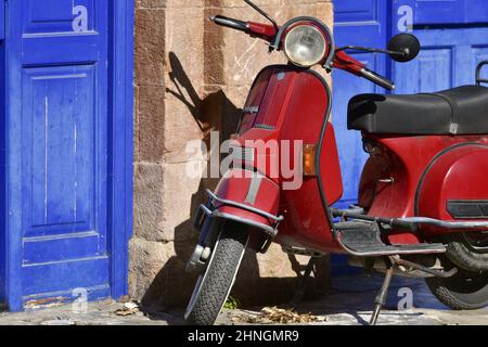 Original red vintage Vespa against a stone wall with blue wooden doors in Nafplio, Peloponnese Greece. Stock Photo