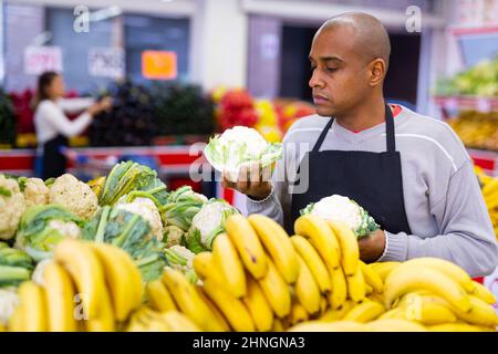 Man working in supermarket near vegetable section Stock Photo