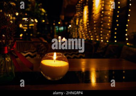 Romantic table setting with burning candle on a restaurant table with illumination and a blurred background Stock Photo