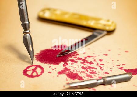 Dip pen nib and spilled red ink forming peace symbol,  depicting that a pen is mightier than a sword. Selective focus photography Stock Photo