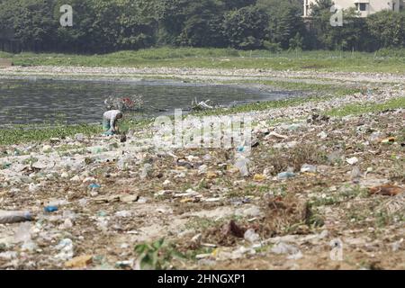 Dhaka, Bangladesh, February 16, 2022. A man collects discarded plastic items on the banks of the river Buriganga, in Dhaka, Bangladesh, February 16, 2022. Industrial waste and sewage from the city are all dumped into the rivers. The once fresh and flowing rivers like Buriganga, is now submerged in pollution. The other rivers of the country face the same fate. Recent research has brought an even more horrendous picture into view. And that is plastic pollution. In just the four rivers that surround the capital city Dhaka, 30,000 tonnes of plastic waste were discovered. Half of this was in the ri Stock Photo