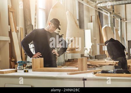 Expert sawdust maker. Portrait of worker doing his job with the wood using grinding machine at his workstation Stock Photo