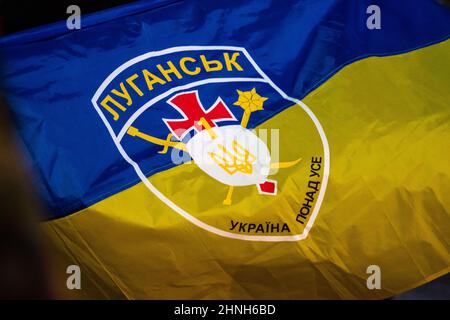 Flag of Ukraine above all with silhouette of symbol or logo of Luhansk or Lugansk city near the border with Russia in the disputed Donbass region Stock Photo