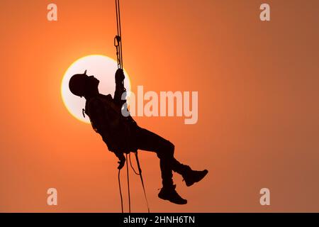 Construction worker wearing safety work at high uniform on scaffolding at construction site on during sunset,Working at height equipment. Stock Photo
