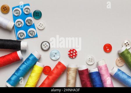 Multi-colored spools of thread with buttons on the table. Flat lay closeup with copy space. Stock Photo