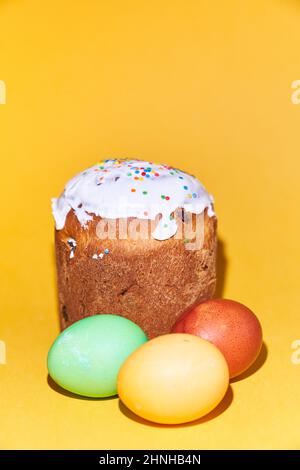 Close-up of colored Easter eggs and a cake on a yellow background. With space to copy. High quality photo Stock Photo