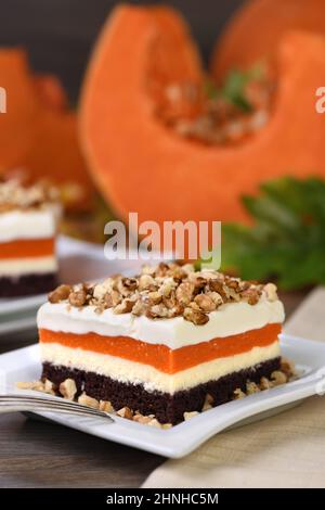 Pumpkin pie - light, creamy dessert with cheese cream and pumpkin layers topped with chopped nuts Stock Photo