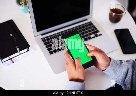 An over the shoulder shot of a young man typing on his mobile phone. Chroma key Stock Photo