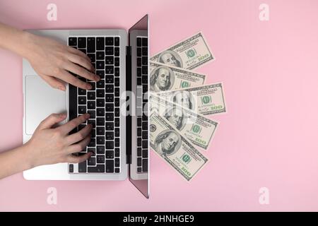 Laptop keyboard and dollar bills. Female hands typing on wireless keyboard, flat lay workspace. Freelance concept, pink background, top view and copy Stock Photo