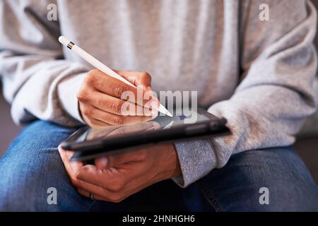 A close up shot of a man's hands using a stylus to draw on a tablet Stock Photo