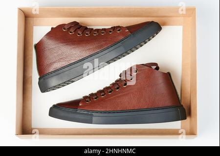 Open paper show box with leather sneakers above top view isolated Stock Photo
