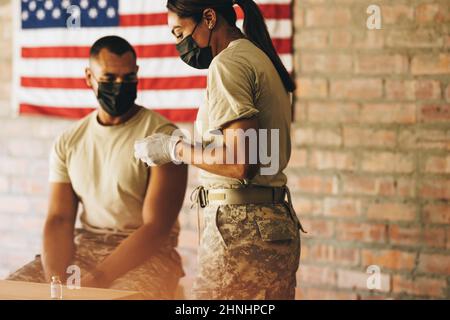 Female doctor preparing to vaccinate a serviceman against coronavirus disease. American military physician preparing to administer an injection of the Stock Photo