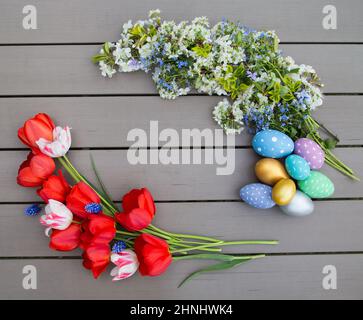 Easter composition of blooming spring branches, tulip flowers, multi-colored painted eggs on a wooden background. place for text. easter holiday decor Stock Photo