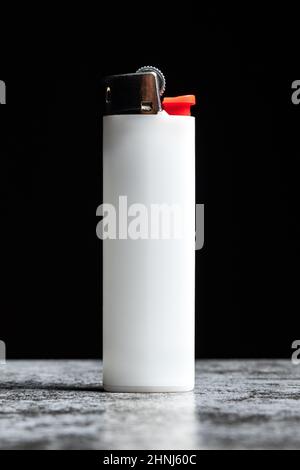 White cigarette lighter on grey table on black background. Stock Photo