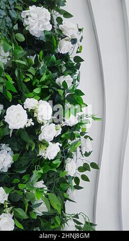 A shrub of European flowers combined with roses and hydrangeas in a room against a white decorative wall. Stock Photo