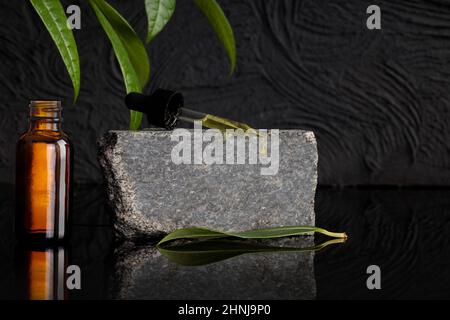 Bottles with dark amber glass of lotion or essential oil and pipette on gray stone. Natural background of products. Beauty salon branding layout. Stock Photo