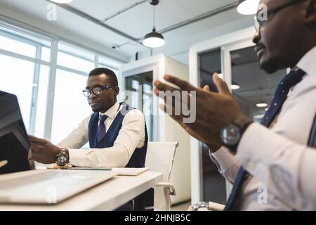 Two African American business partners are working on a laptop together on a joint project. Mutual assistance and establishment of social contacts Stock Photo