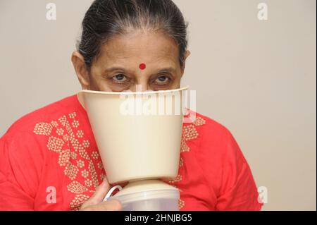 Mumbai Maharashtra India Asia June 29 2021 Elderly woman using a steam inhaler inhaling a decongestant for colds and bronchitis. Stock Photo