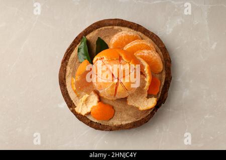 Board with mandarin and leaves on light textured background Stock Photo